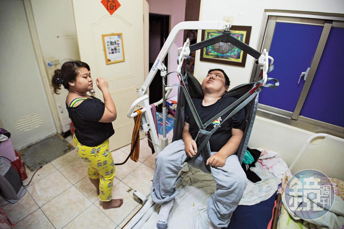 劉于濟（右）罹患肌萎症，無法自理生活，外傭24小時不離，晚上也須同房以便照顧。早上起床，外傭（左）需操作移位機，才能將他挪到輪椅上。