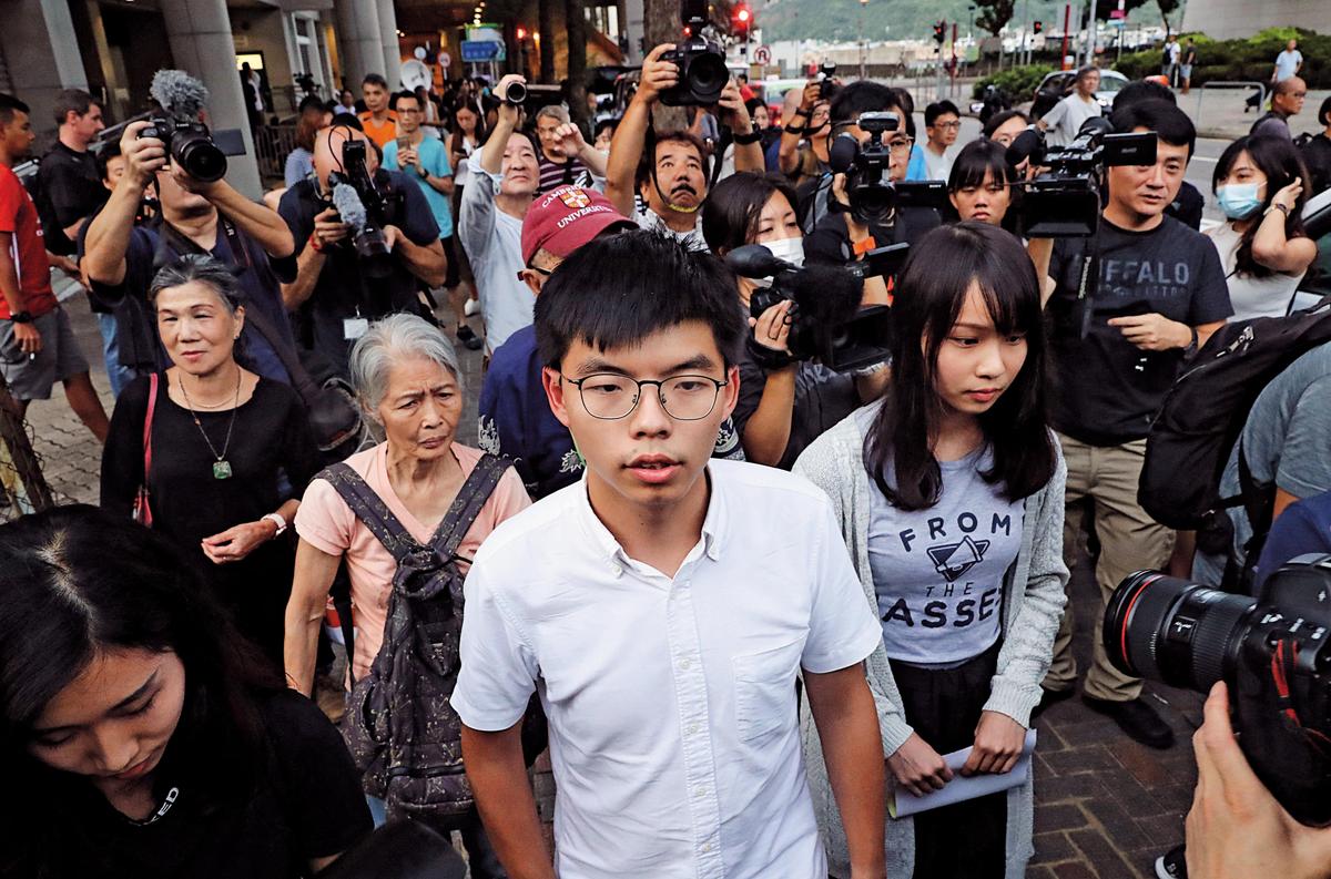 香港众志秘书长黄之锋（前中）及另一成员周庭（前右）日前因涉及621包围警察总部一事被捕。（达志影像）