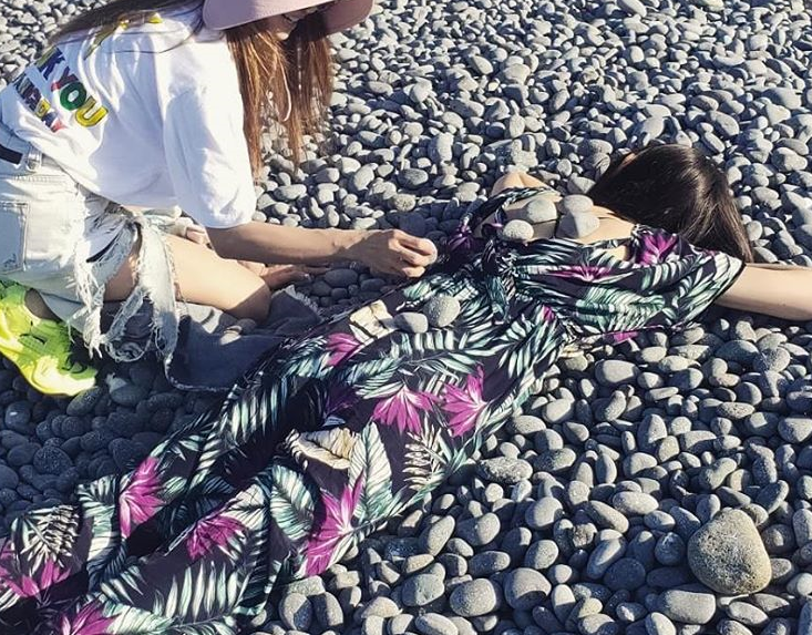 蔡依林穿著黑紫花圖案連身洋裝趴在石頭地上，享受日光浴。（翻攝自蔡依林IG）