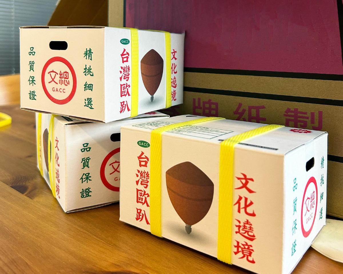 以台灣常見的紅白配色水果箱，作為陀螺的外包裝，配上黃色封箱繩與產品標示等設計，充滿濃濃台味。（圖／文化總會提供）