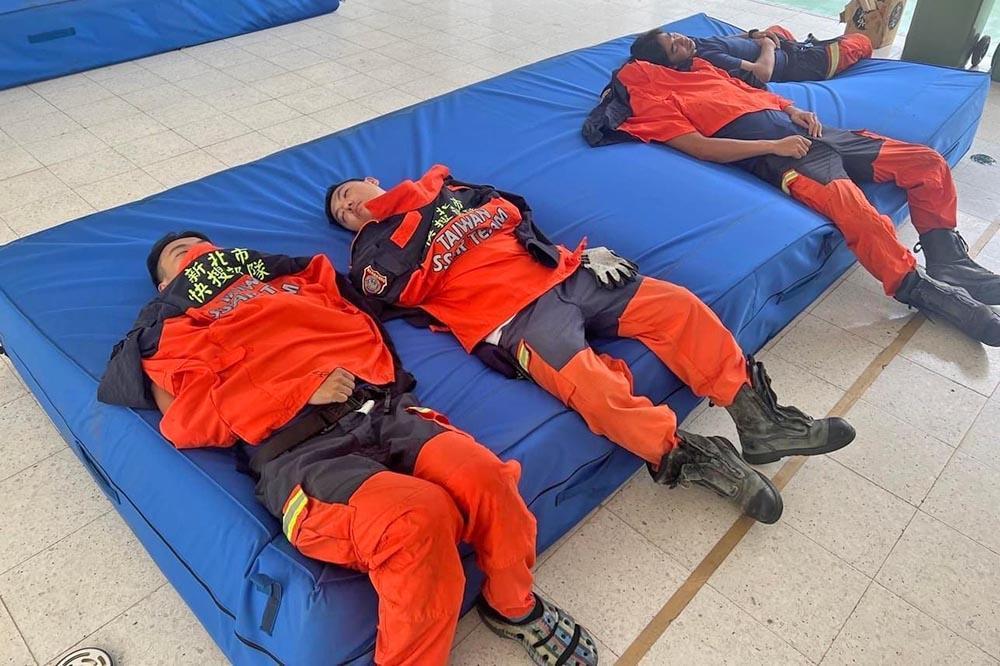 搜救隊員累癱，僅簡單以外套蓋著躺在跳高墊上「瞇一下」。（翻攝自新北消防發爾麵）
